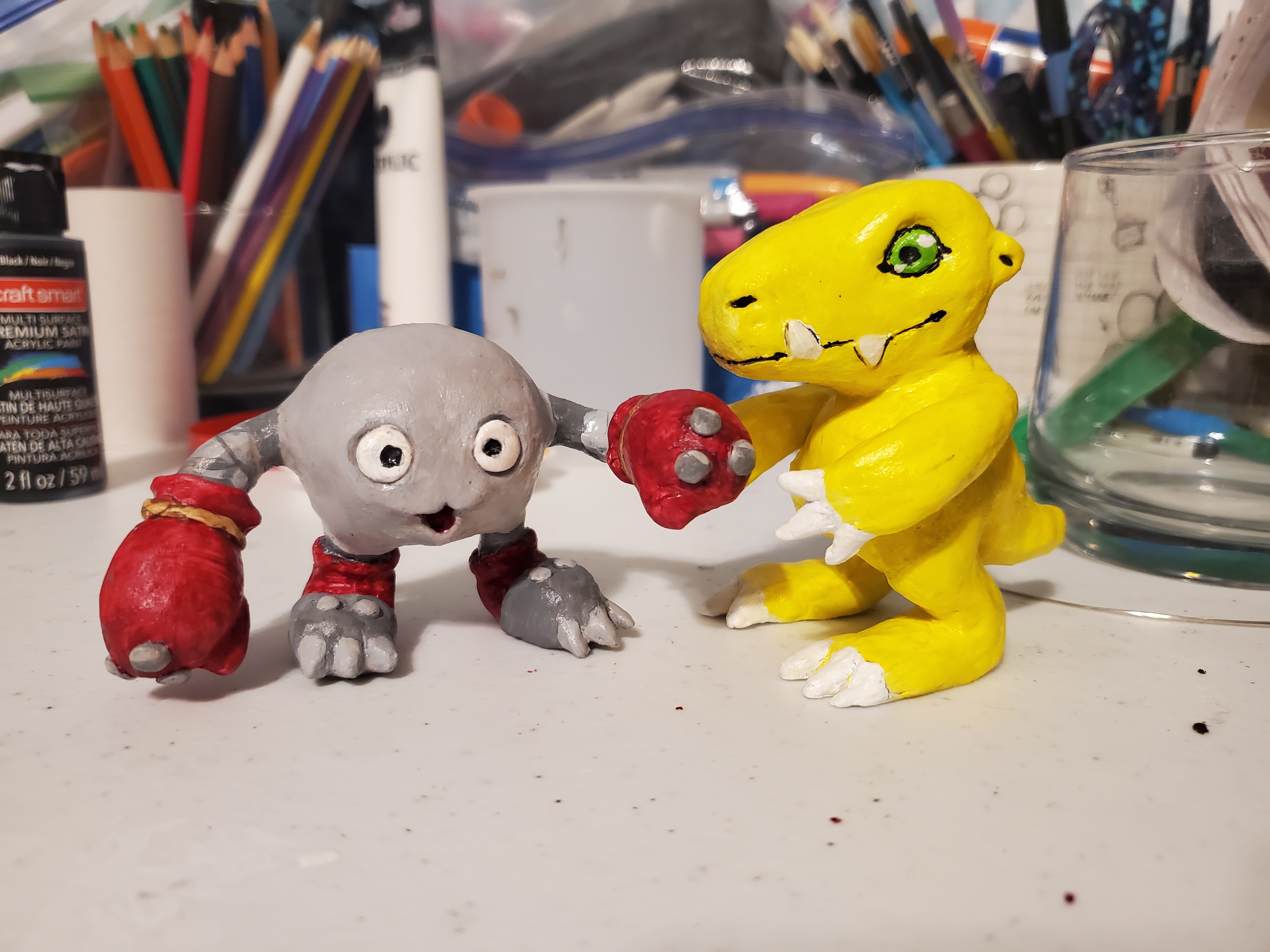A pair of clay figures of Mamemon and Agumon from Digimon